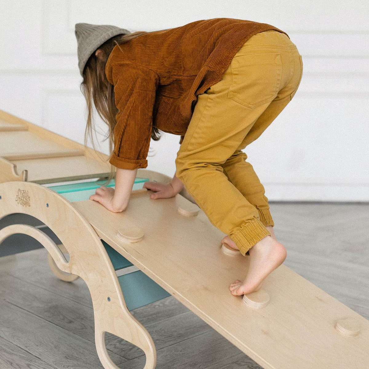 Child playing on Montessori set with climbing ladder and slide in mint color, made of birch plywood.