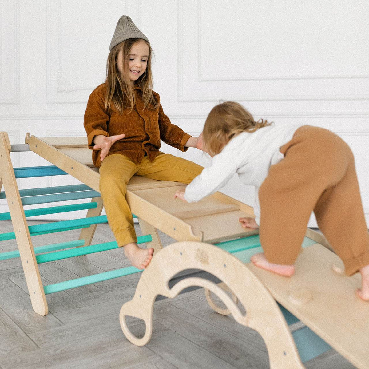 Montessori children&#39;s play set with climbing triangle, slides, and swing in mint color.
