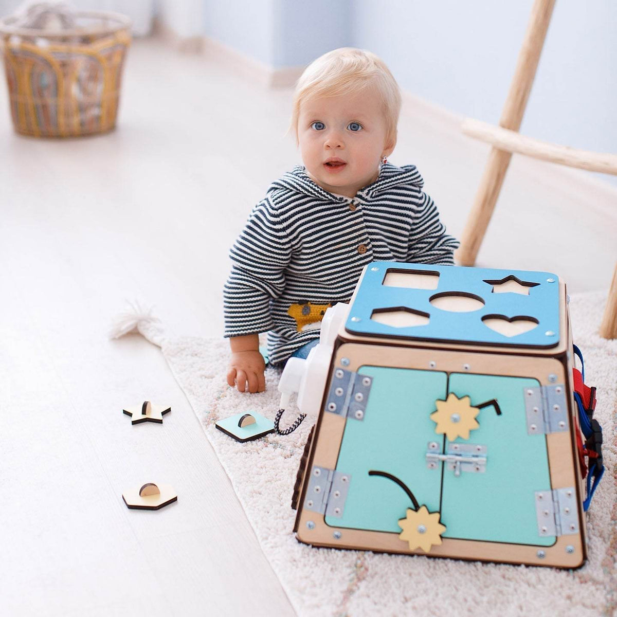 Montessori Holzspielzeug Activity Board with toddler engaging in learning activities on a colorful busy board, promoting fine motor skills and logical thinking.