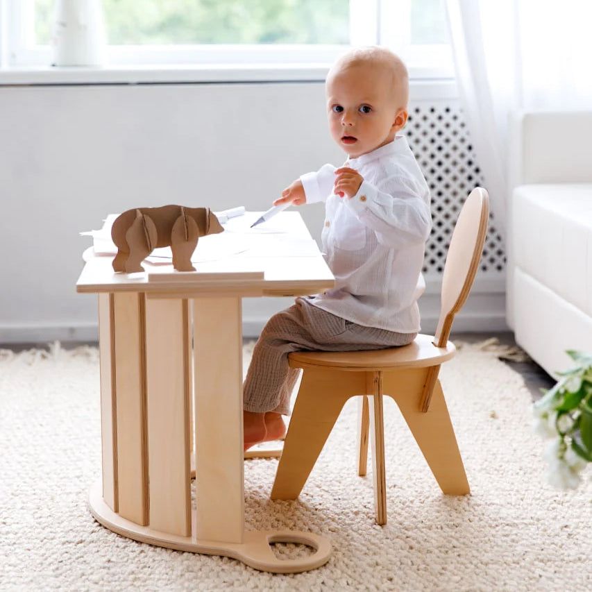 Toddler using wooden balance rocker with board for motor skill development.
