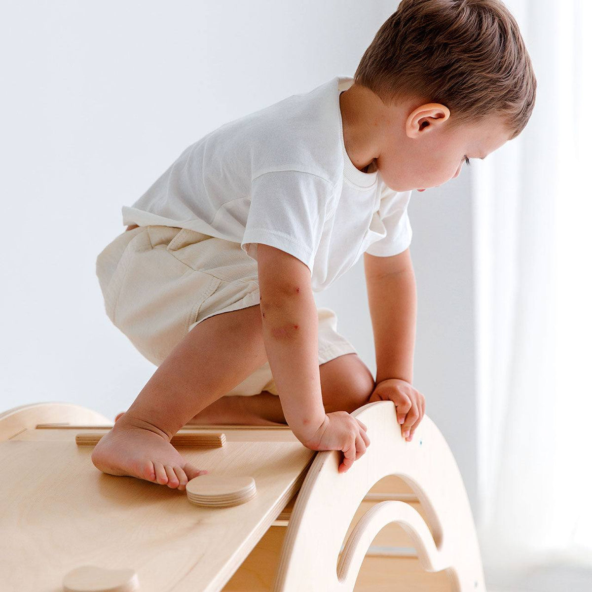 Child playing on Montessori wooden balance rocker with dual-sided board made of birch plywood.