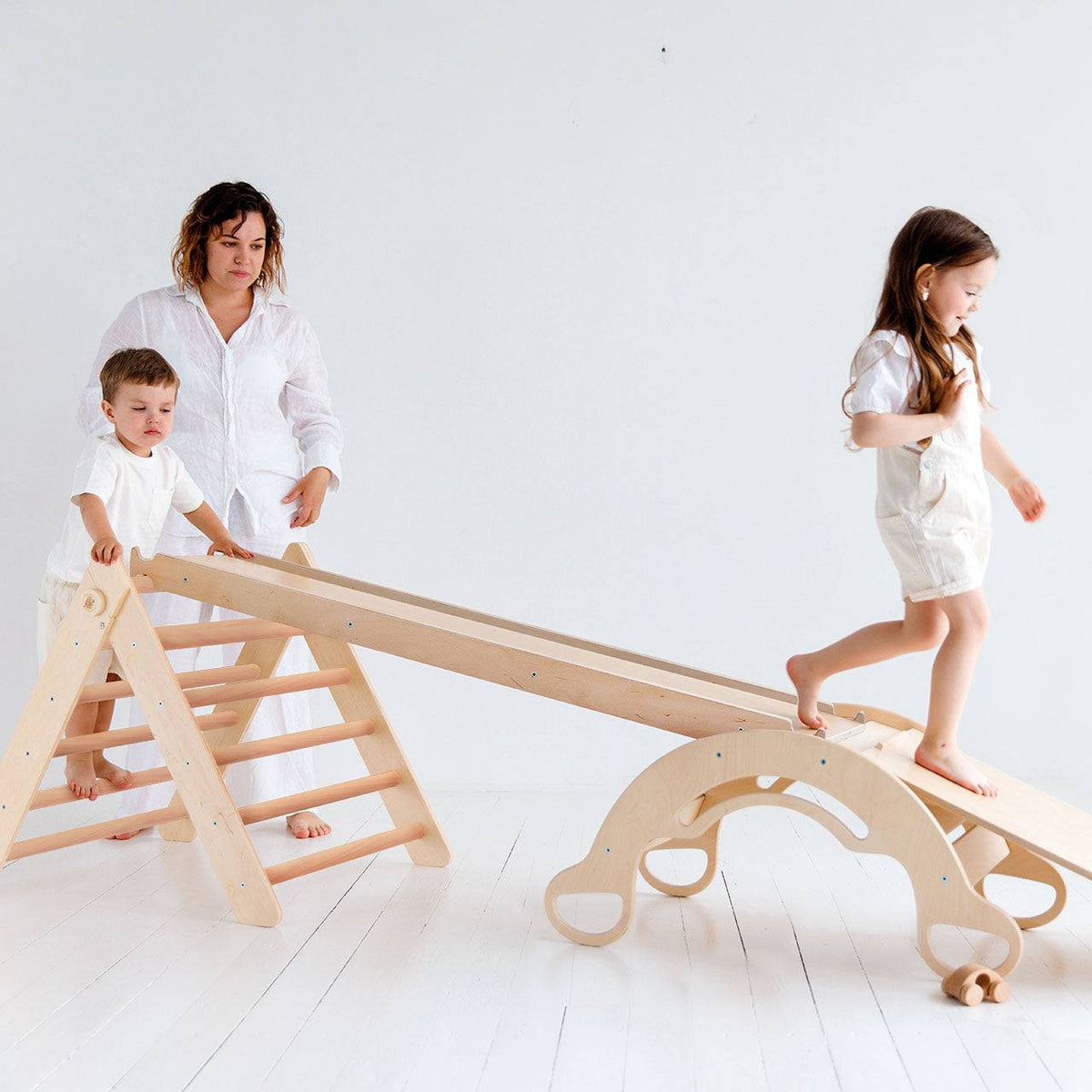Children playing on a natural Pikler triangle set with ramps and balance rocker.