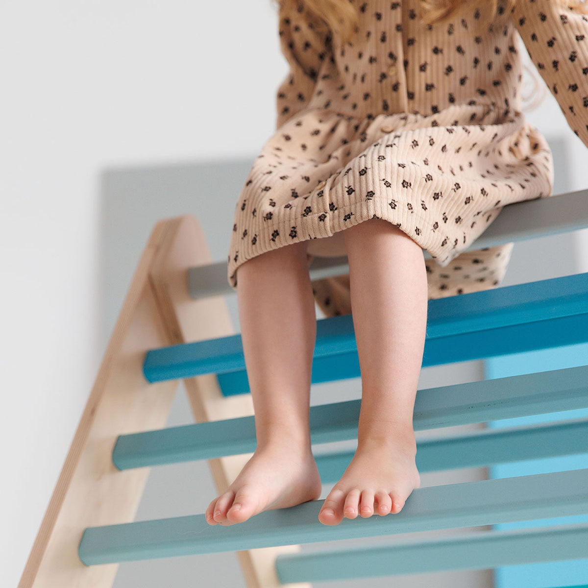 Child playing on Montessori® Kletterdreieck climbing toy in mint color.