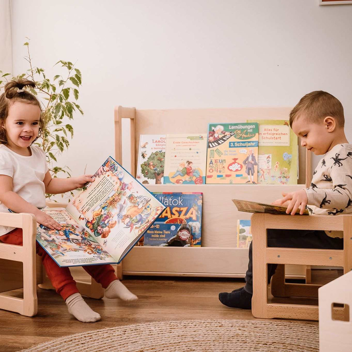 Children using Montessori Bücherregal Midi, a wooden bookshelf for organizing books.