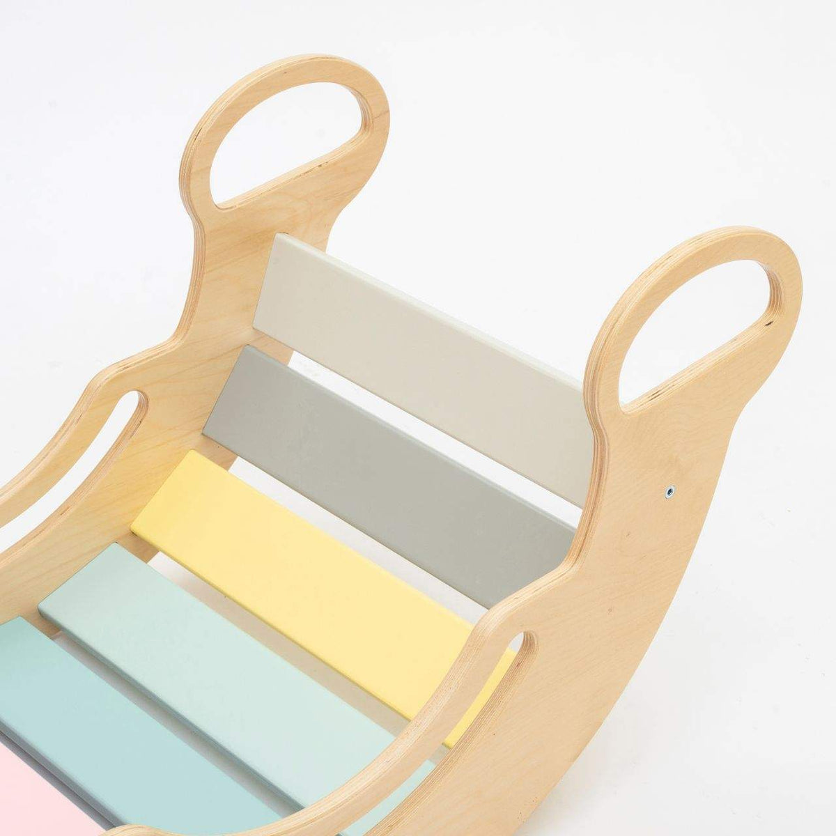 Pastel-colored balance rocker made from birch plywood with handles.