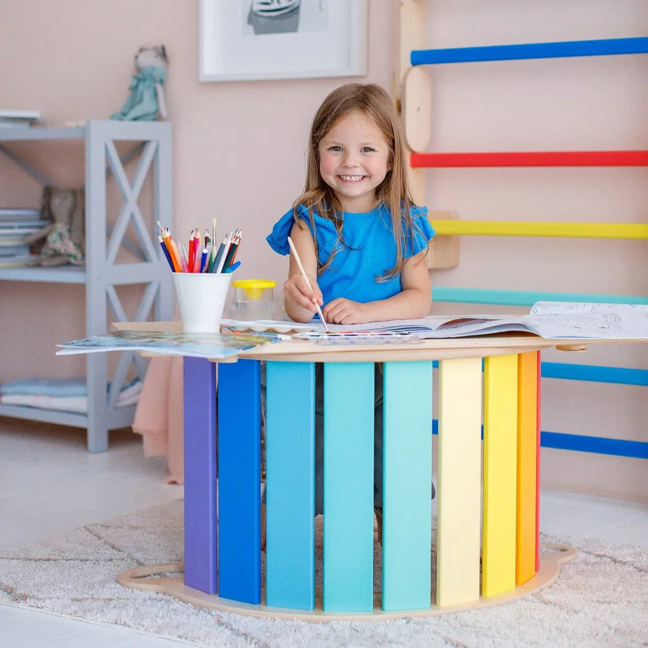 Montessori Balancewippe/Rocker in bright colors with a child playing and smiling.