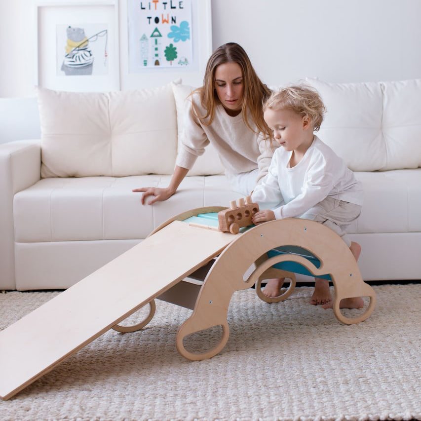 Child using mint play set with rocker board and mini chair indoors.