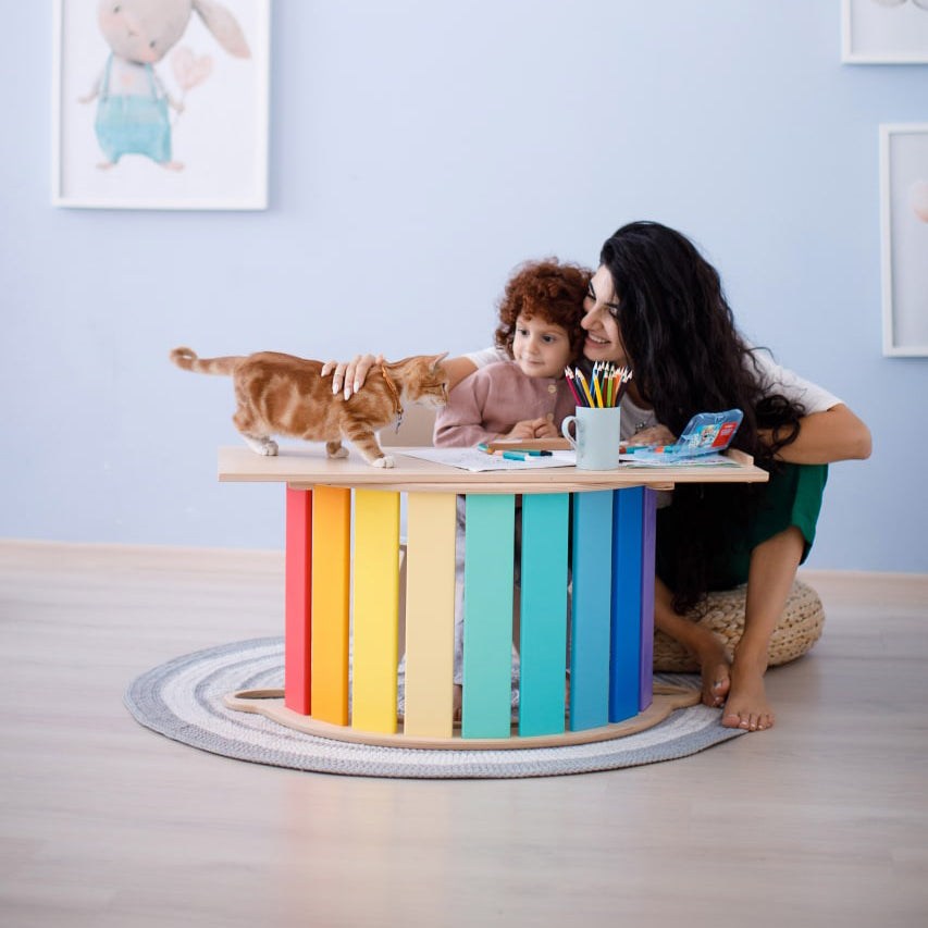 Brightly colored set with a wobble board, double-sided board, and mini chair, featuring child playing with a cat in a cozy room.