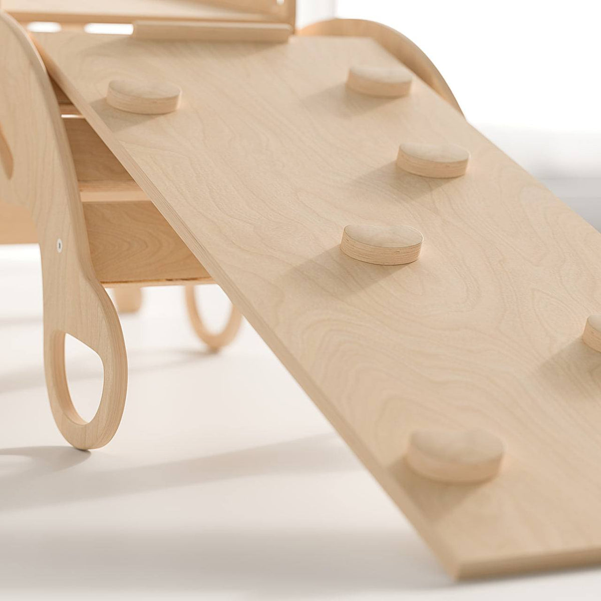 Wooden climbing set with Pikler triangle, slides, and balance rocker, uncoated natural finish.