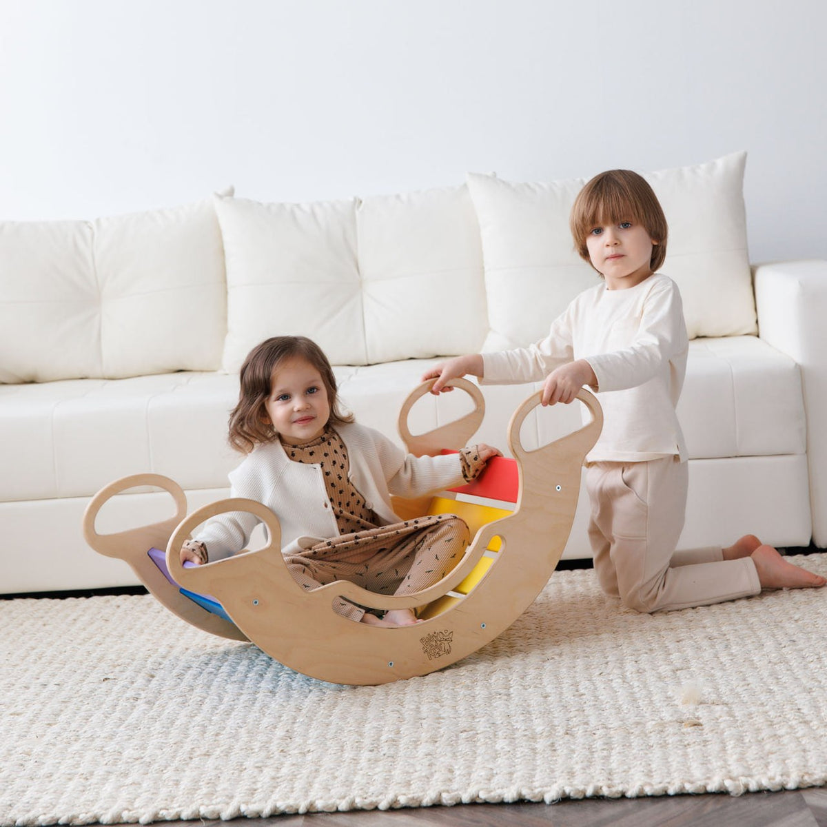 Children playing on a multifunctional wooden rocker in bright colors.