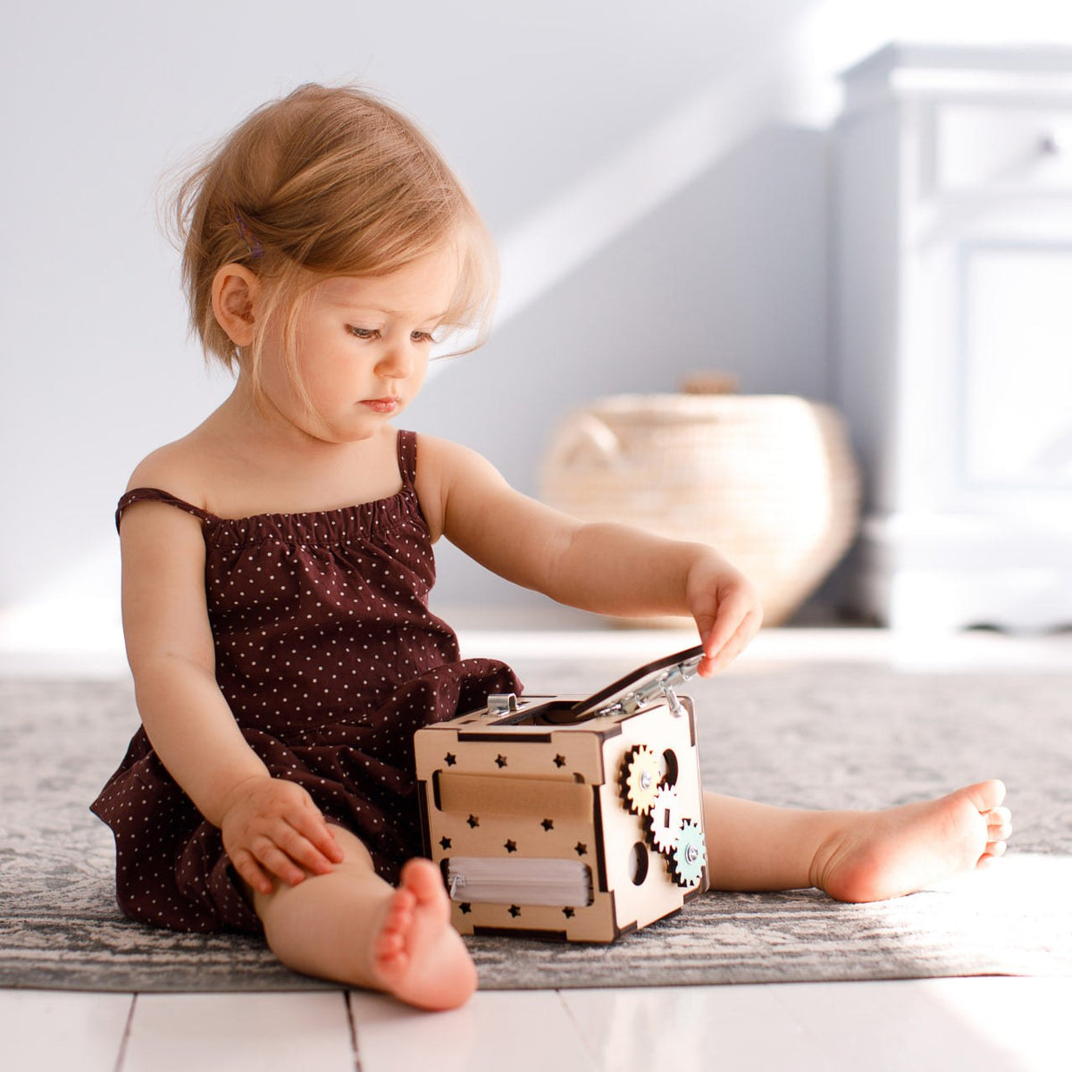 Toddler playing with Kreativer Würfel wooden interactive learning toy on carpet.