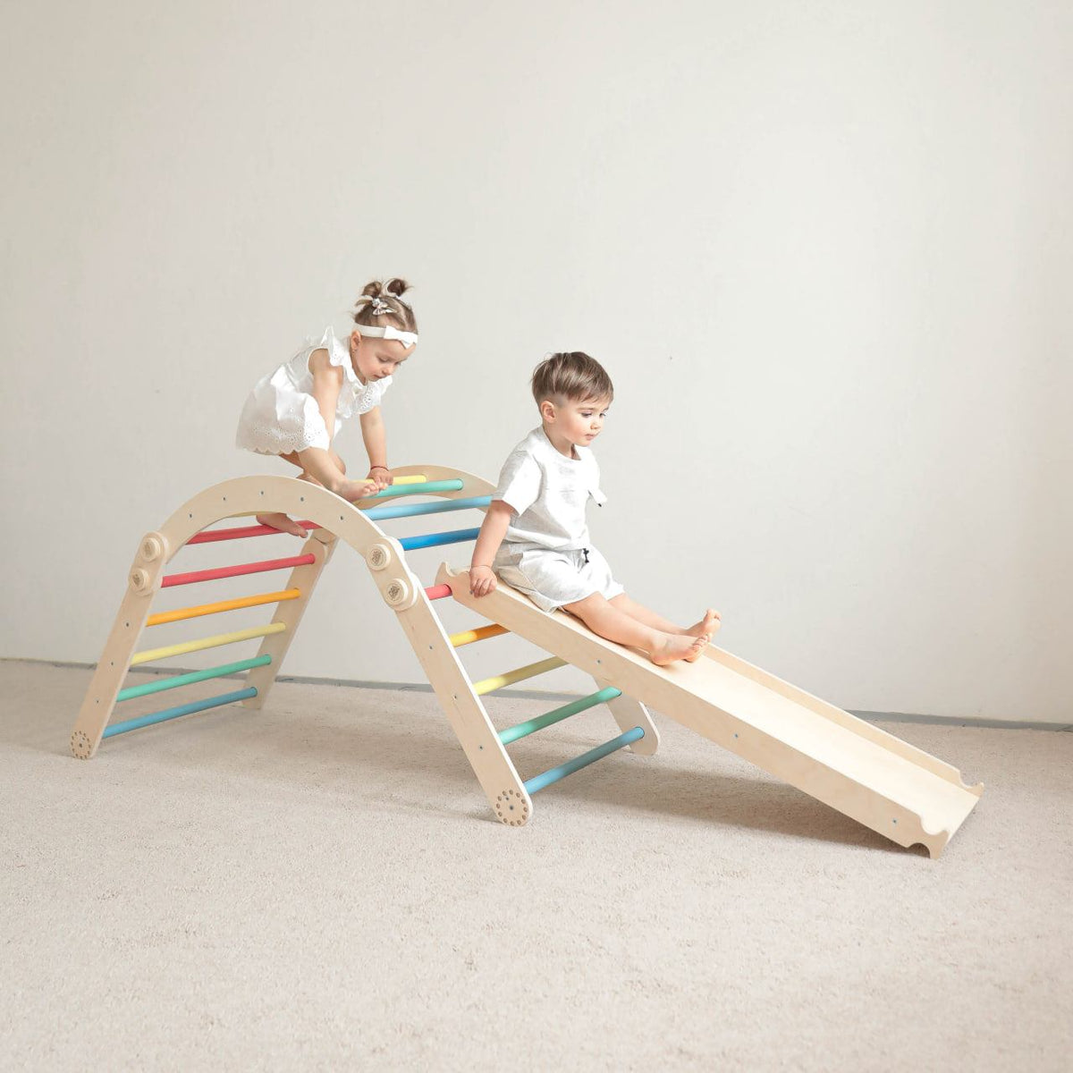 Children playing on a rainbow-colored climbing frame set with a slide.