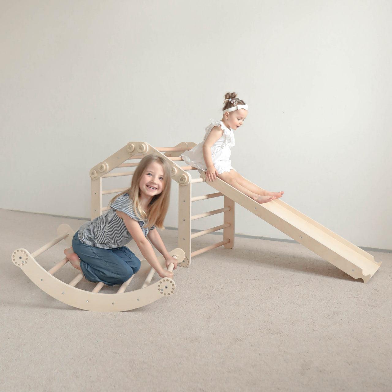Children playing on a natural wood climbing frame set with slide.
