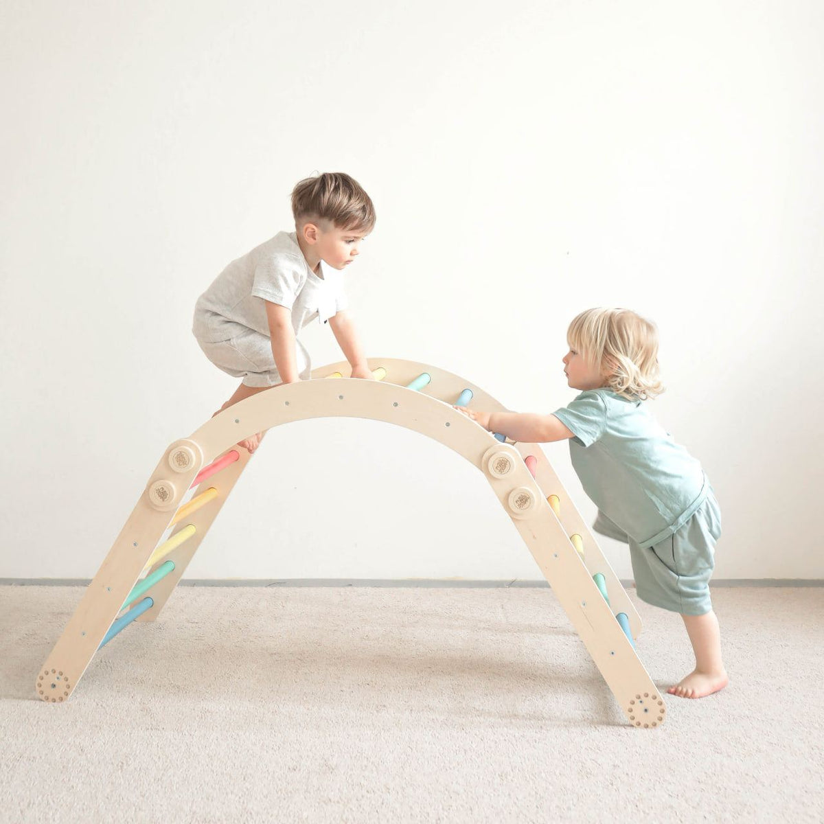 Children playing on rainbow-colored climbing frame set with swing.