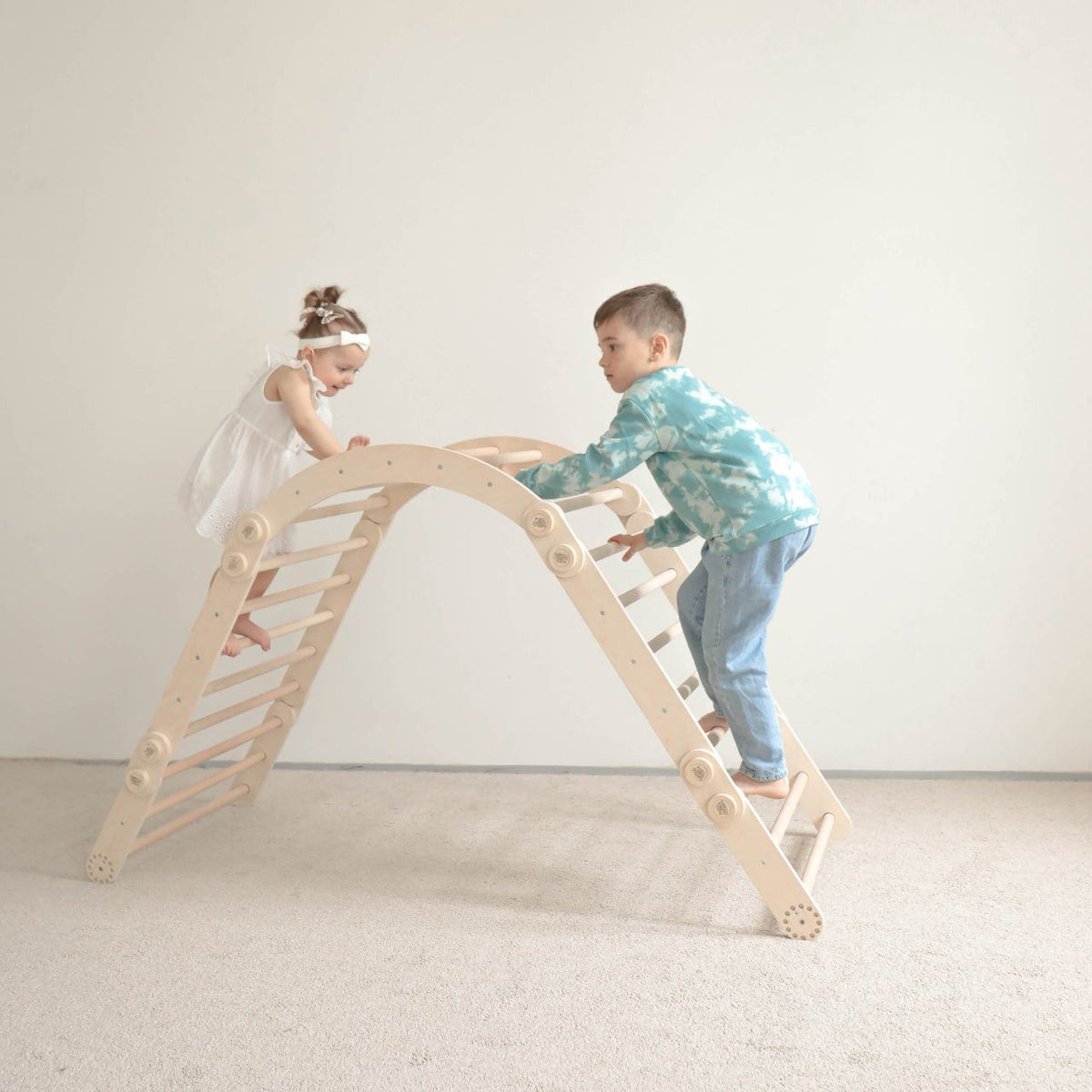 Children playing on a natural wooden climbing frame set with swing.