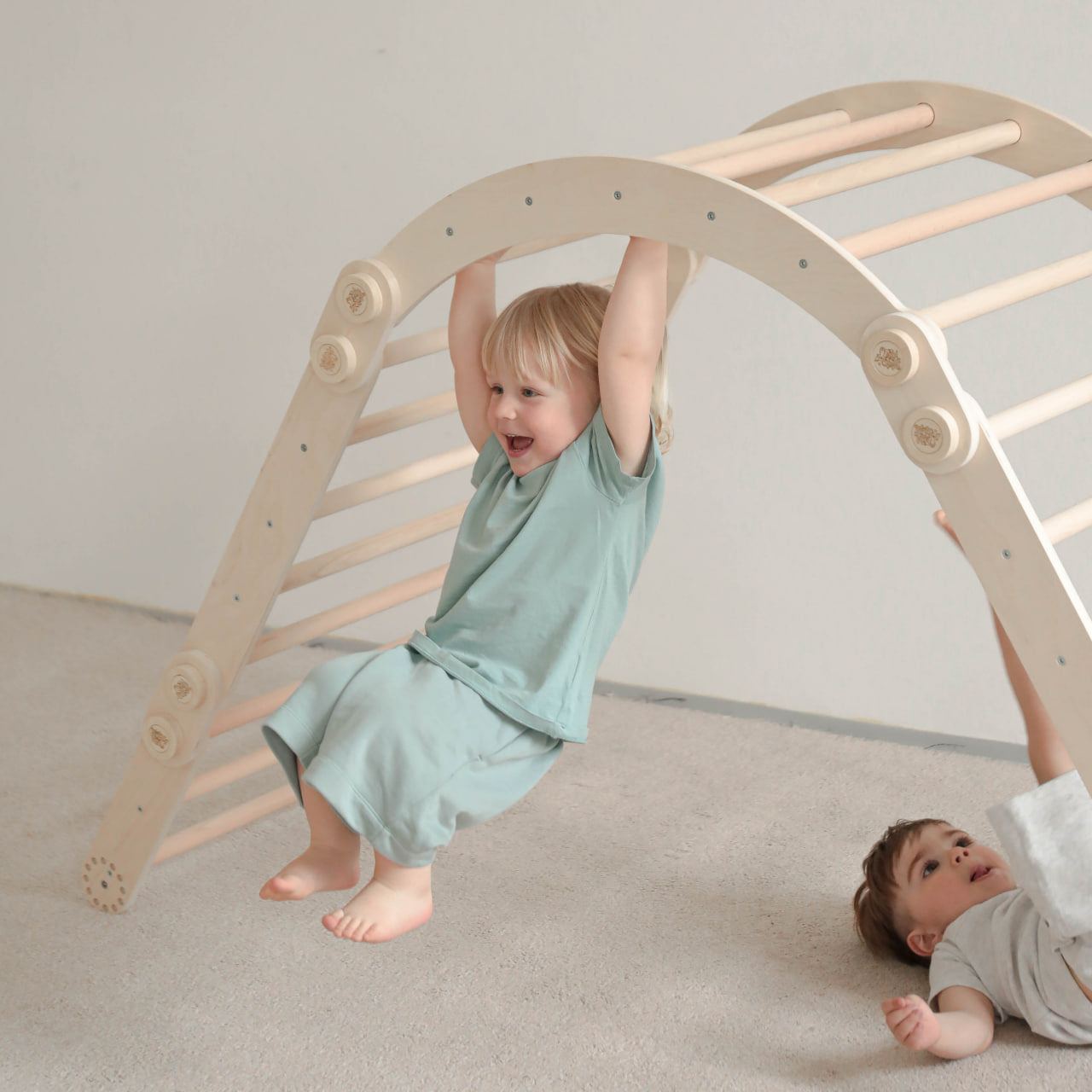 Children playing on a natural wooden climbing frame set with a swing, designed for versatile motor skill development.