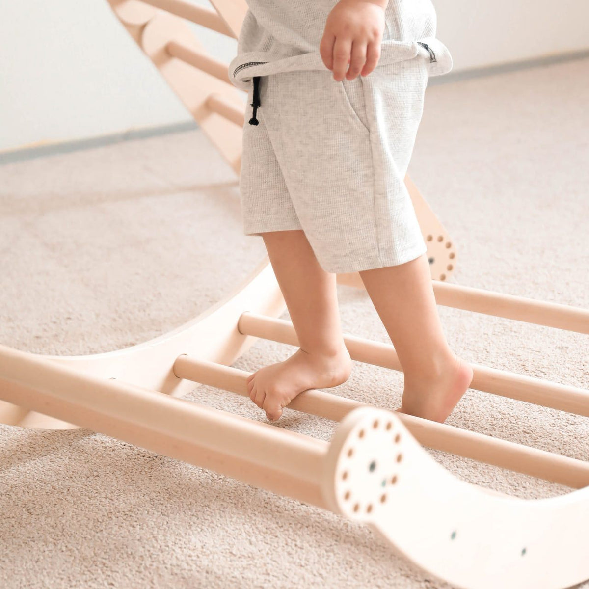 Child climbing on natural wooden playset, showcasing grooved climbing structure.