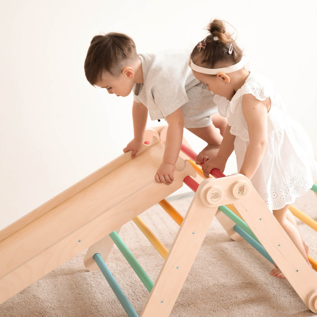 Children playing on wooden climbing set with slide and colorful bars indoors.