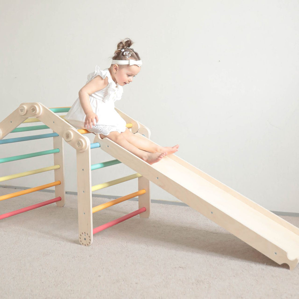 Children&#39;s flexible climbing frame set with slide in light color, featuring rainbow rungs.