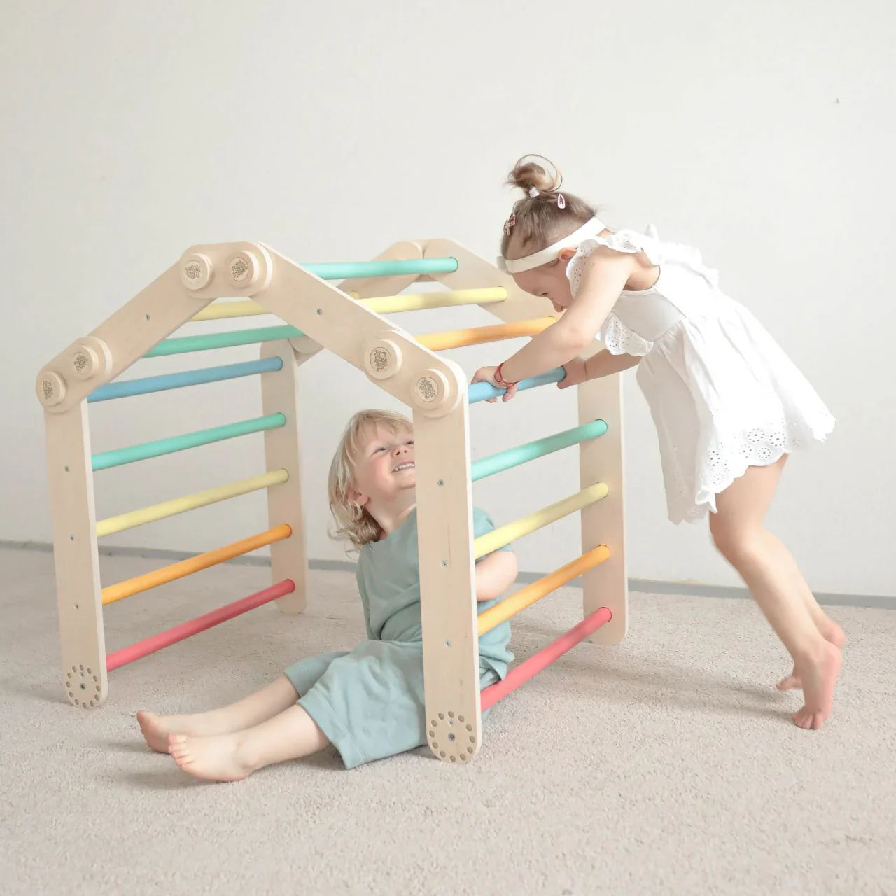 Children playing with a vibrant, adjustable climbing frame set indoors.