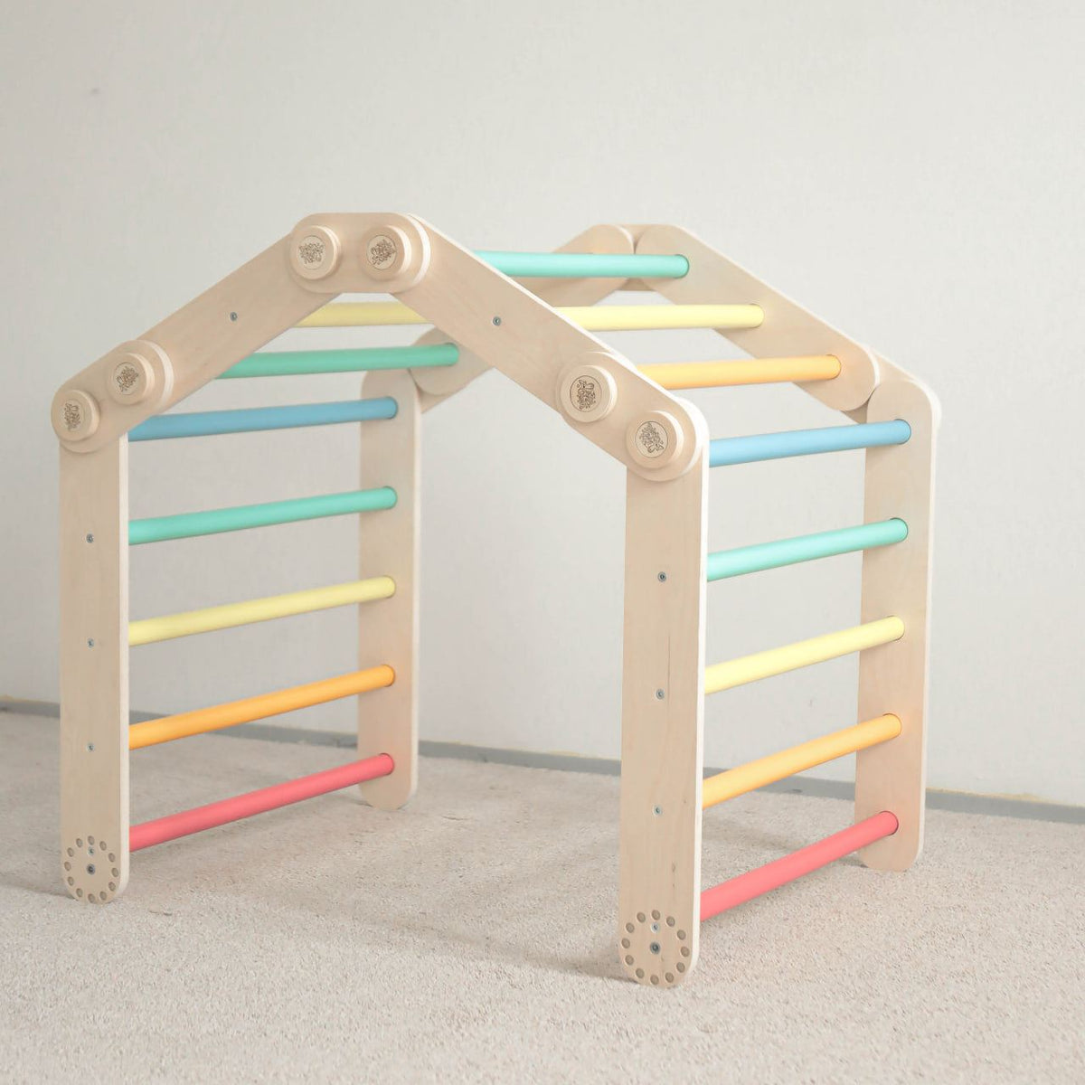 Colorful children&#39;s climbing frame made of birch wood with two Pikler triangles, promoting motor skills.