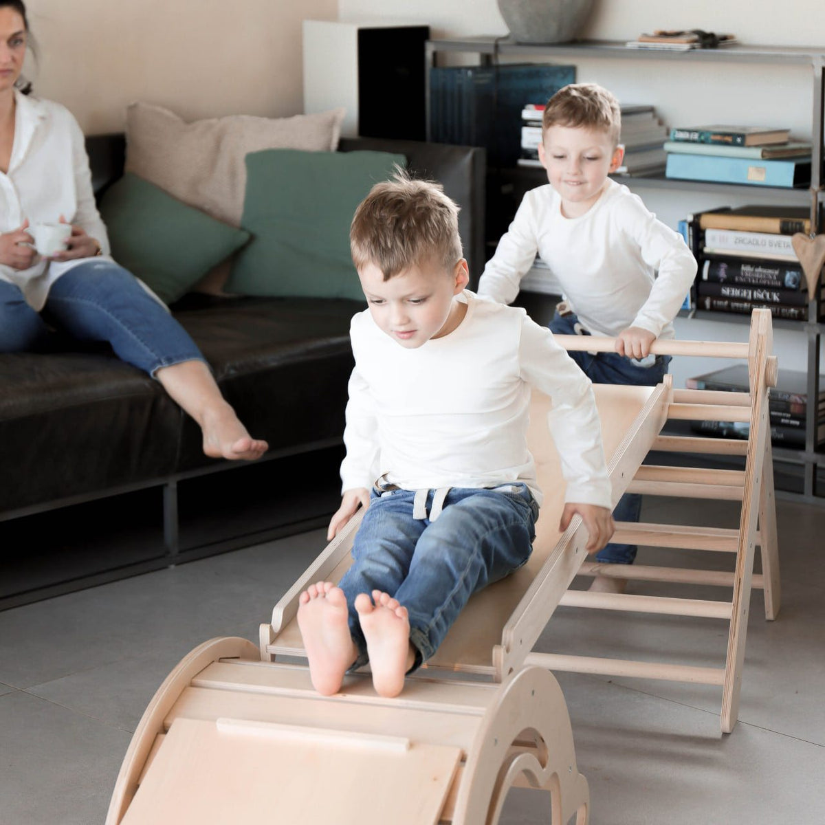 Children playing on a wooden Pikler triangle set indoors.