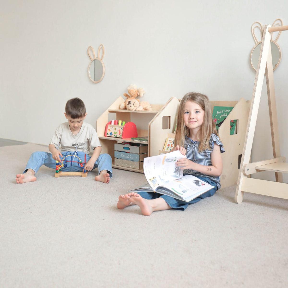 Children&#39;s Montessori Bücherregal &amp; Spielzeugregal in a playroom with kids reading and playing.