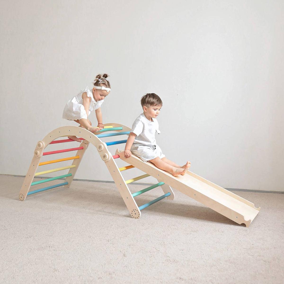 Children playing on a colorful climbing frame set with slide indoors.