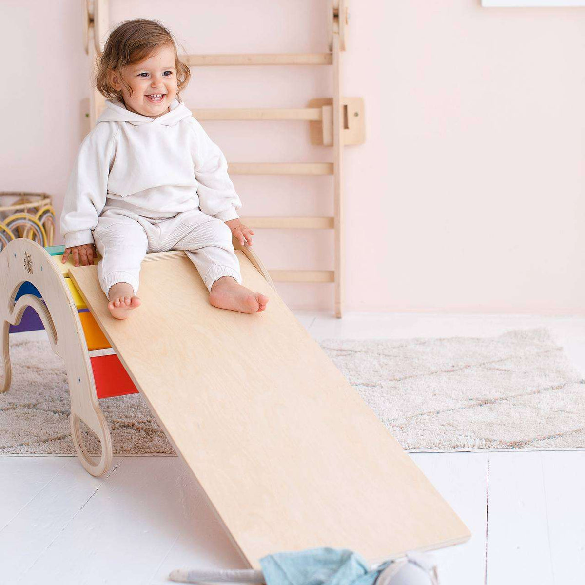 Child playing on Montessori balance rocker with double-sided wooden board in bright birch, promoting motor skills development.