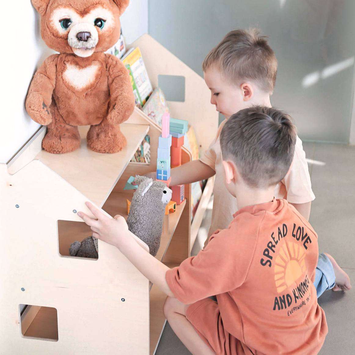 Children playing with books and toys on a Montessori Bücherregal &amp; Spielzeugregal in a nursery room.
