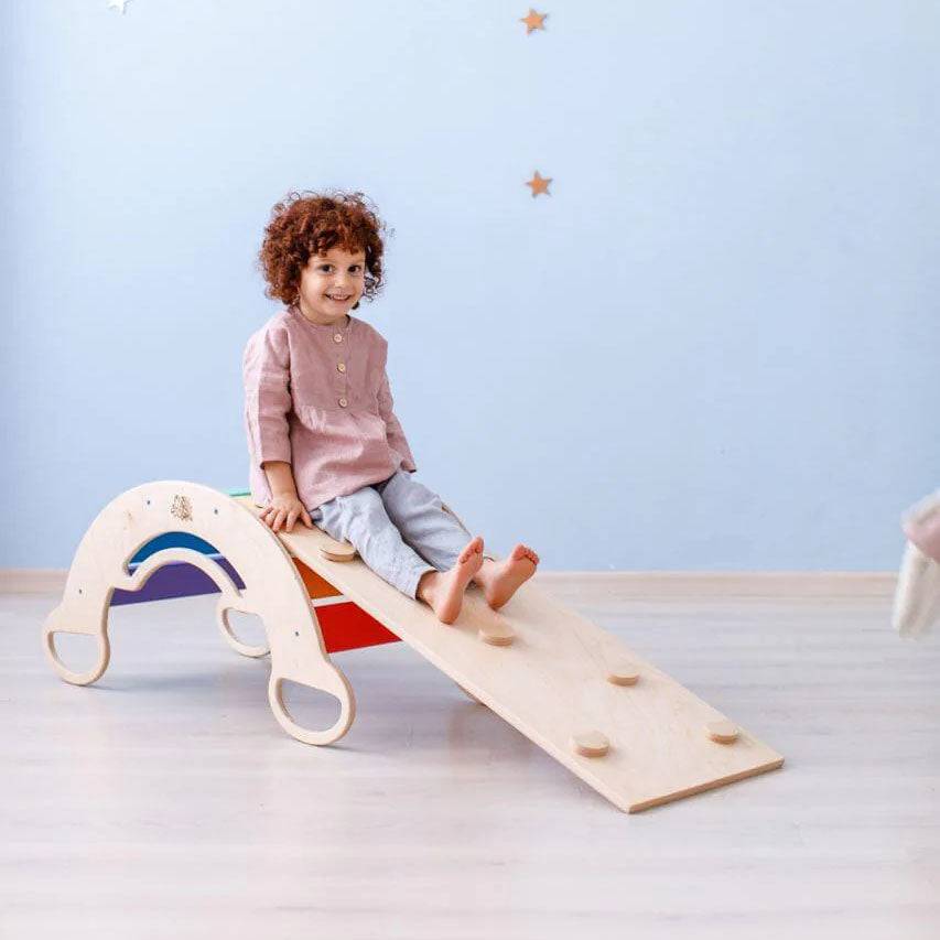 Montessori Balancewippe aus Birkensperrholz mit Kind spielend darauf.